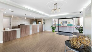 Un hall d’entrée spacieux avec un comptoir de réception, un plancher en bois et un lustre moderne.