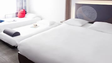 A hotel room with two beds, a red toy, a framed artwork, and a window with curtains.