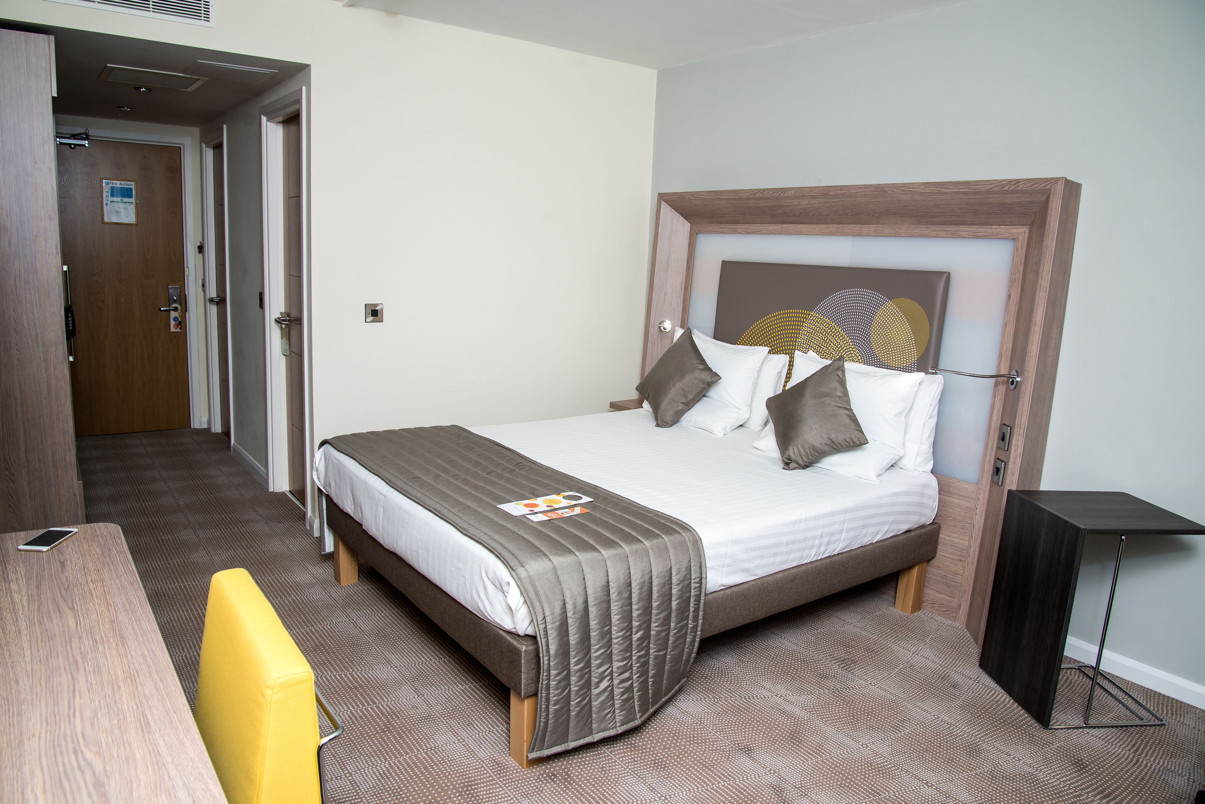Una habitación de hotel con cama, mesita de noche y una silla.