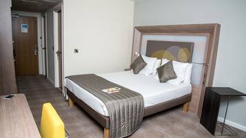 Una habitación de hotel con cama, mesita de noche y una silla.