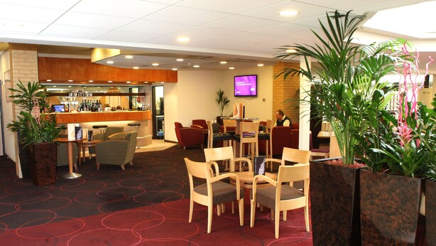 A hotel lobby with a reception desk, seating area, and a bar.