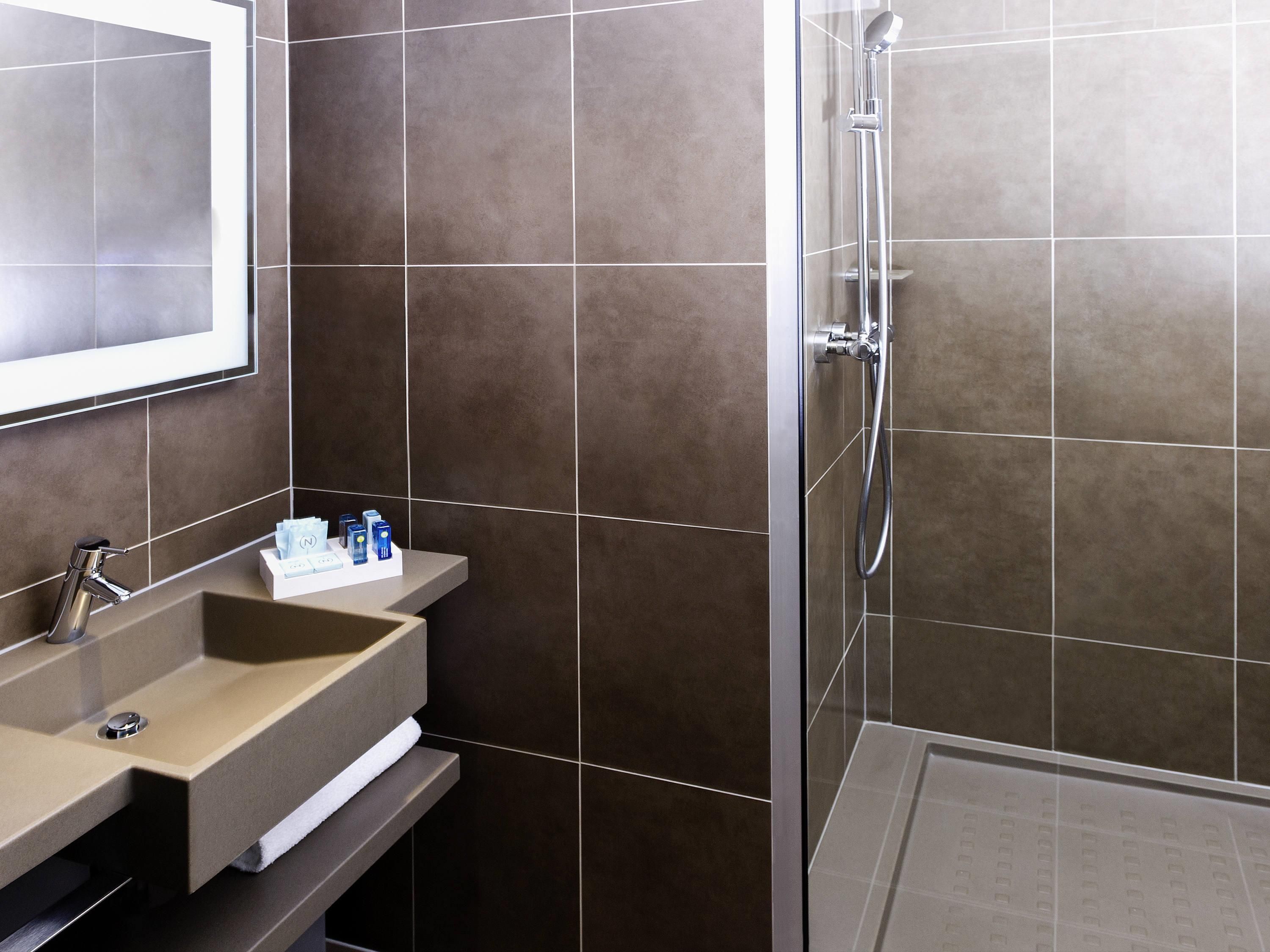 A modern bathroom with a sink, mirror, and shower.