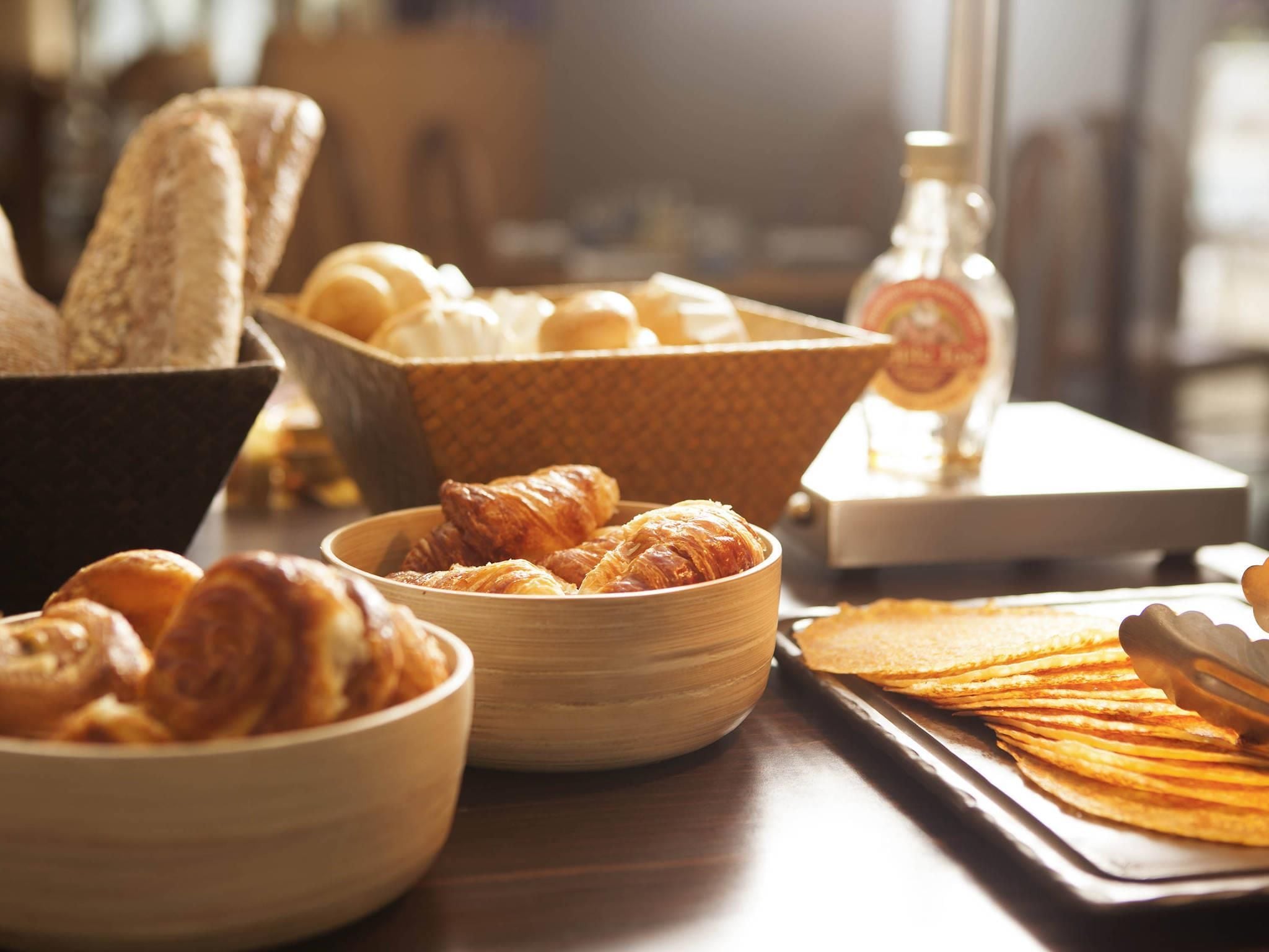 Een ontbijtbuffet met diverse gebakken producten, waaronder brood, croissants en gebak.