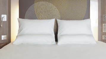 A bed with white pillows and a headboard with a geometric pattern.