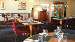 A restaurant with multiple tables and chairs, some with blue placemats.