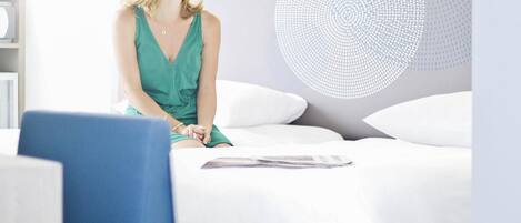 A woman sitting on a bed with a magazine, in a room with a modern design and a circular light fixture on the wall.