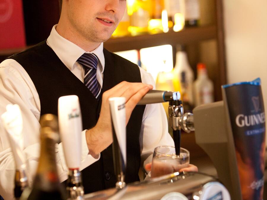 Un cantinero en un bar con múltiples grifos de cerveza y un grifo de Guinness.