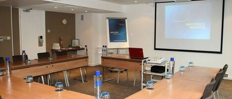 A conference room with a long table, chairs, a projector screen, and a welcome banner.