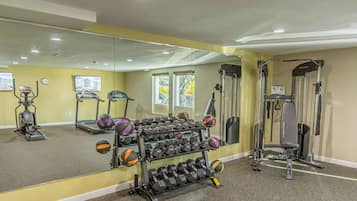A gym with exercise equipment, a mirror, and a rack of dumbbells.