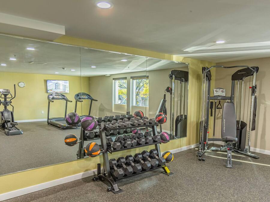 A gym with exercise equipment, a mirror, and a rack of dumbbells.