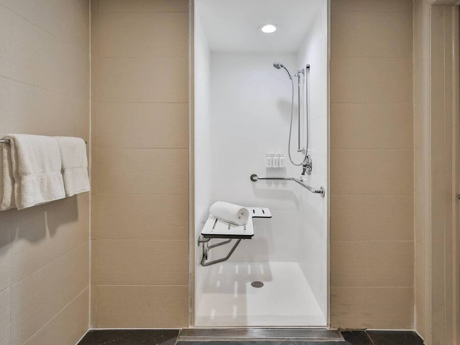 A modern bathroom with a glass-enclosed shower, a towel rack, and a small shelf with a towel.