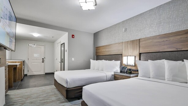 A hotel room with two beds, a desk, a chair, a lamp, and a flat-screen TV. - The Penn Stroud, Stroudsburg - Poconos, an Ascend Collection Hotel (Stroudsburg)