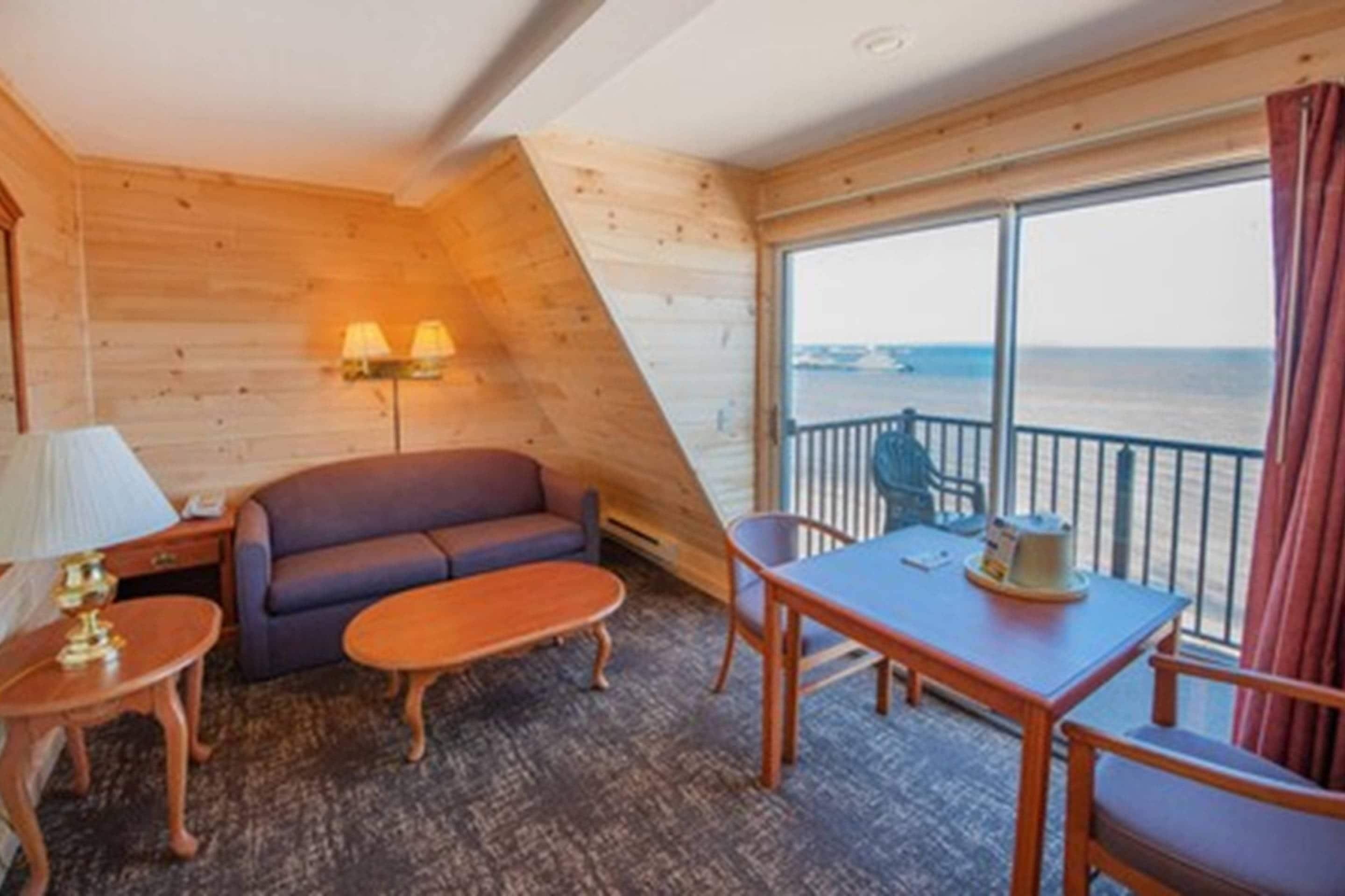 A cabin with a sofa, a small table, a lamp, and a view of the sea.