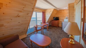 A cozy cabin room with a wooden interior, a small table with chairs, a sofa, a lamp, and a TV. - Quality Inn & Suites Mackinaw City Beachfront (Mackinaw City)