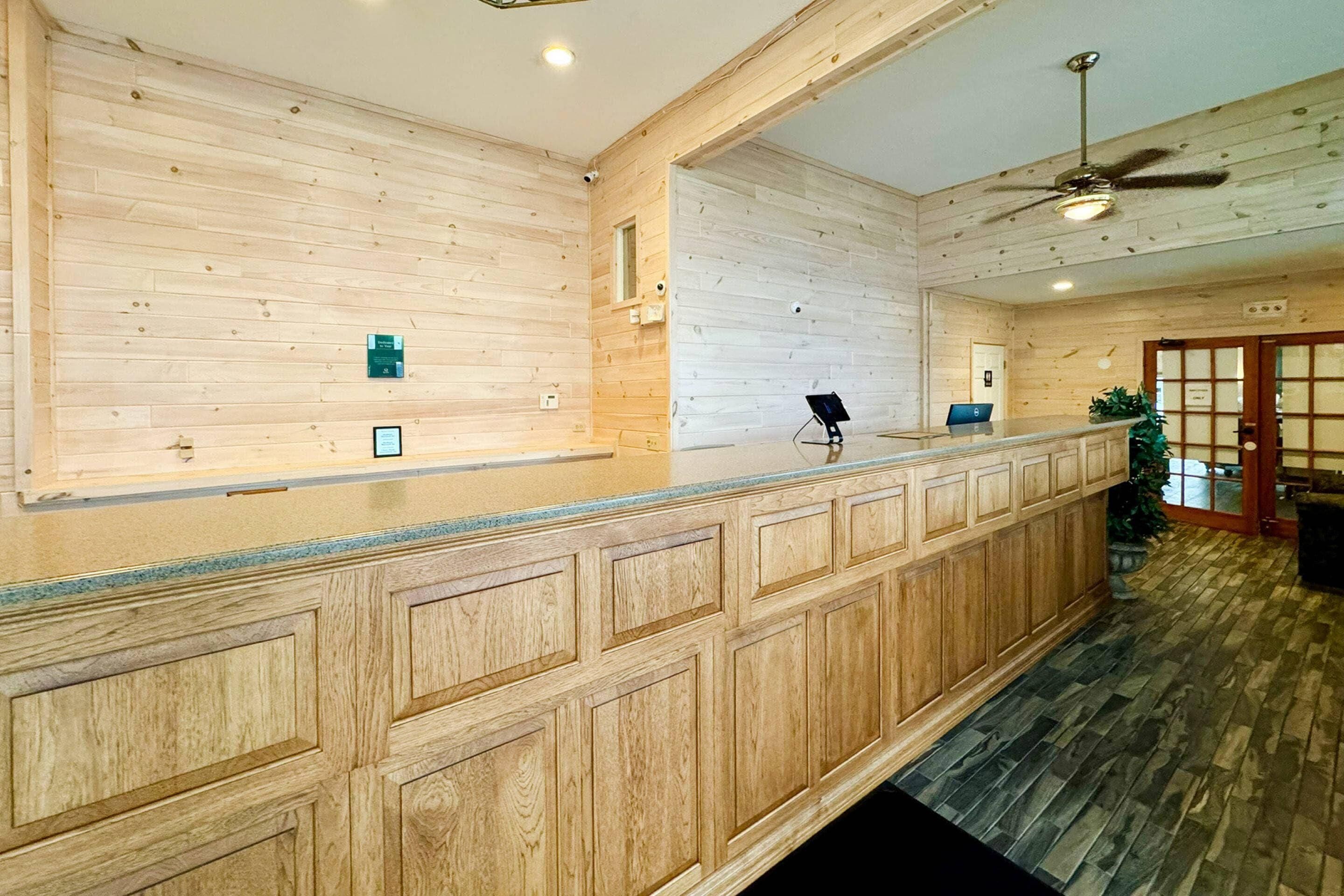 A reception area with a wooden panel wall, a ceiling fan, and a reception desk.