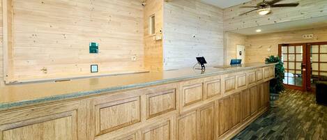 A reception area with a wooden panel wall, a ceiling fan, and a reception desk.