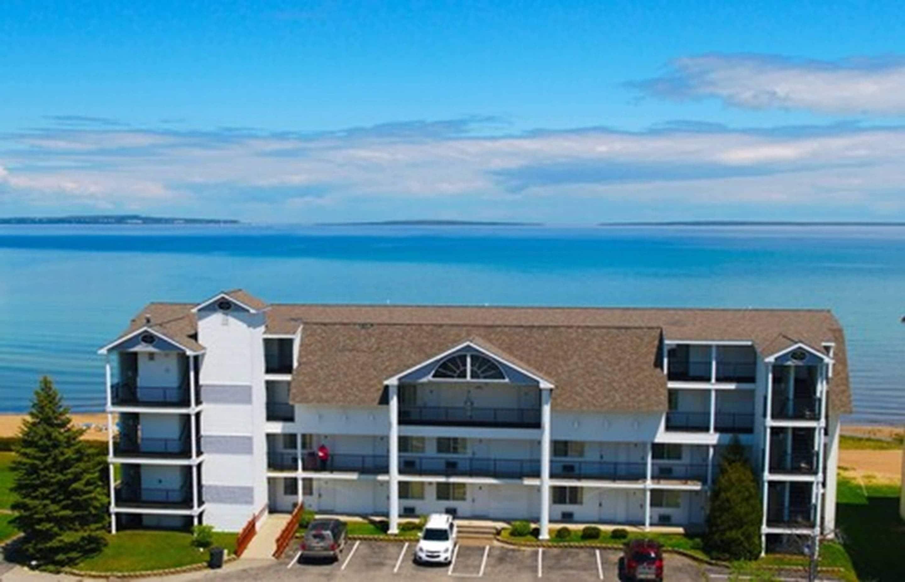 A multi-story hotel with a flat roof, located near a body of water.