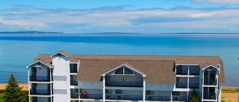 A multi-story hotel with a flat roof, located near a body of water.