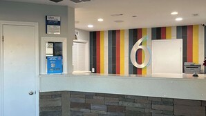 A reception area with a stone wall, a colorful striped wall, and a large number '6' sign. - Motel 6 Greenville, NC – ECU-Medical Center (Greenville)
