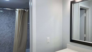 A bathroom with a bathtub, toilet, and a sink with a mirror. - Motel 6 Greenville, NC – ECU-Medical Center (Greenville)