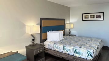 Une chambre d’hôtel avec un lit, deux tables de chevet, un banc et un tableau encadré au mur.