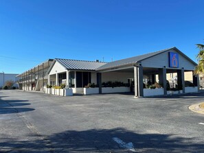 A motel with a covered parking area, a clear sky, and a sign indicating a maximum clearance of 9'7". - Motel 6 Greenville, NC – ECU-Medical Center (Greenville)