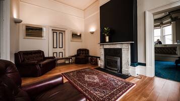 A spacious living room with a fireplace, leather sofas, and a patterned rug.