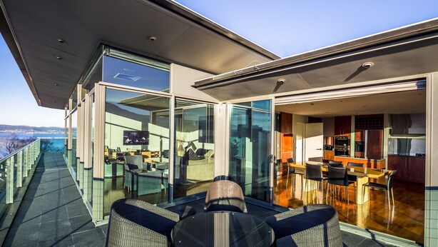 Un interior moderno con comedor, cocina y puertas de vidrio que dan a un balcón exterior.
