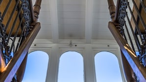 Un escalier avec des balustrades en bois et un plafond blanc agrémenté de lucarnes.