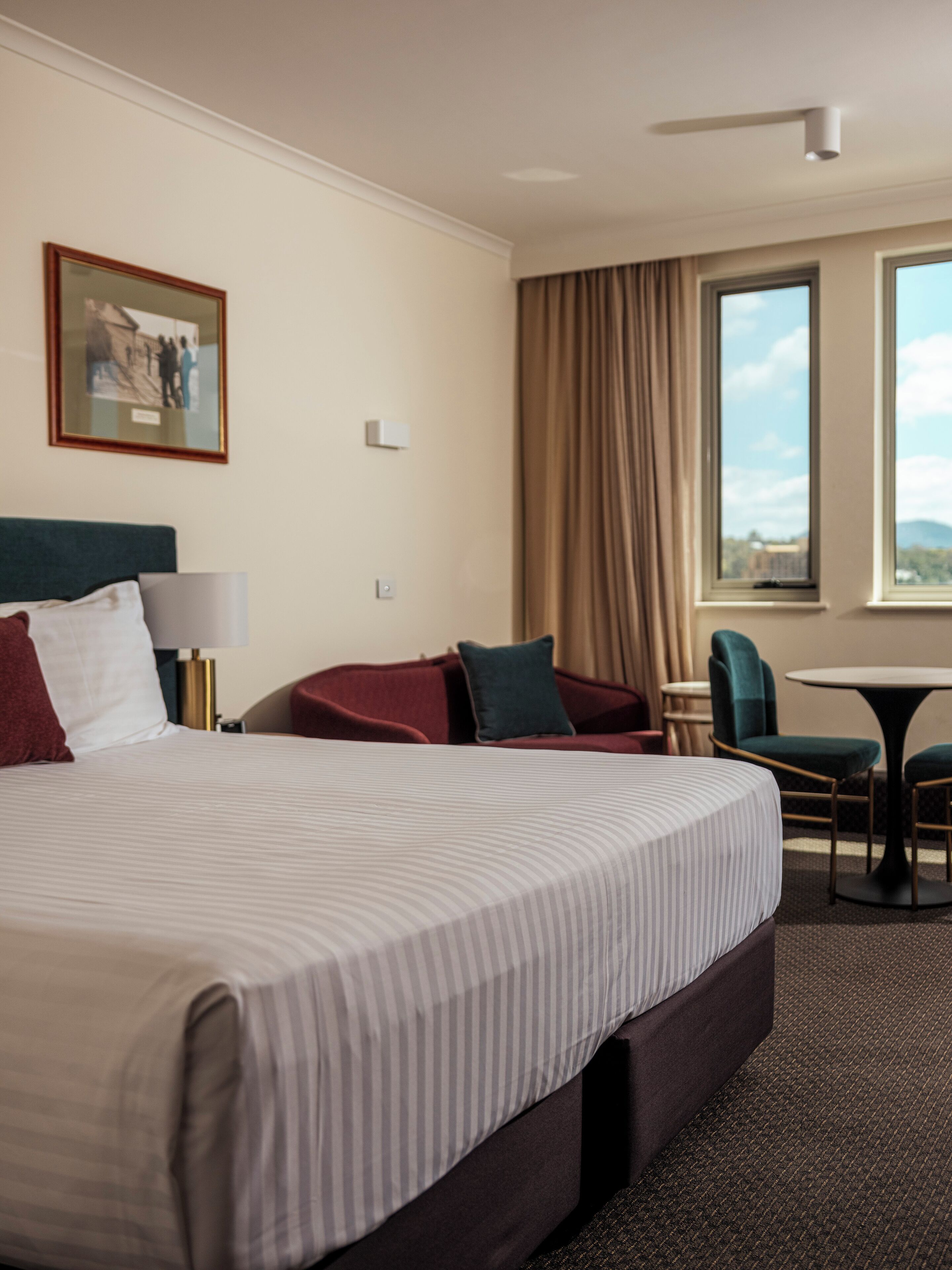 Een hotelkamer met een groot bed, een bureau, een stoel en een raam met uitzicht.