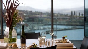 Una mesa de comedor con vistas a un paisaje urbano y un cuerpo de agua.