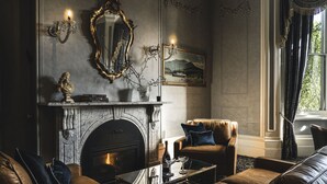 Un salon luxueux avec une cheminée, des canapés en cuir, une table basse et un grand miroir.
