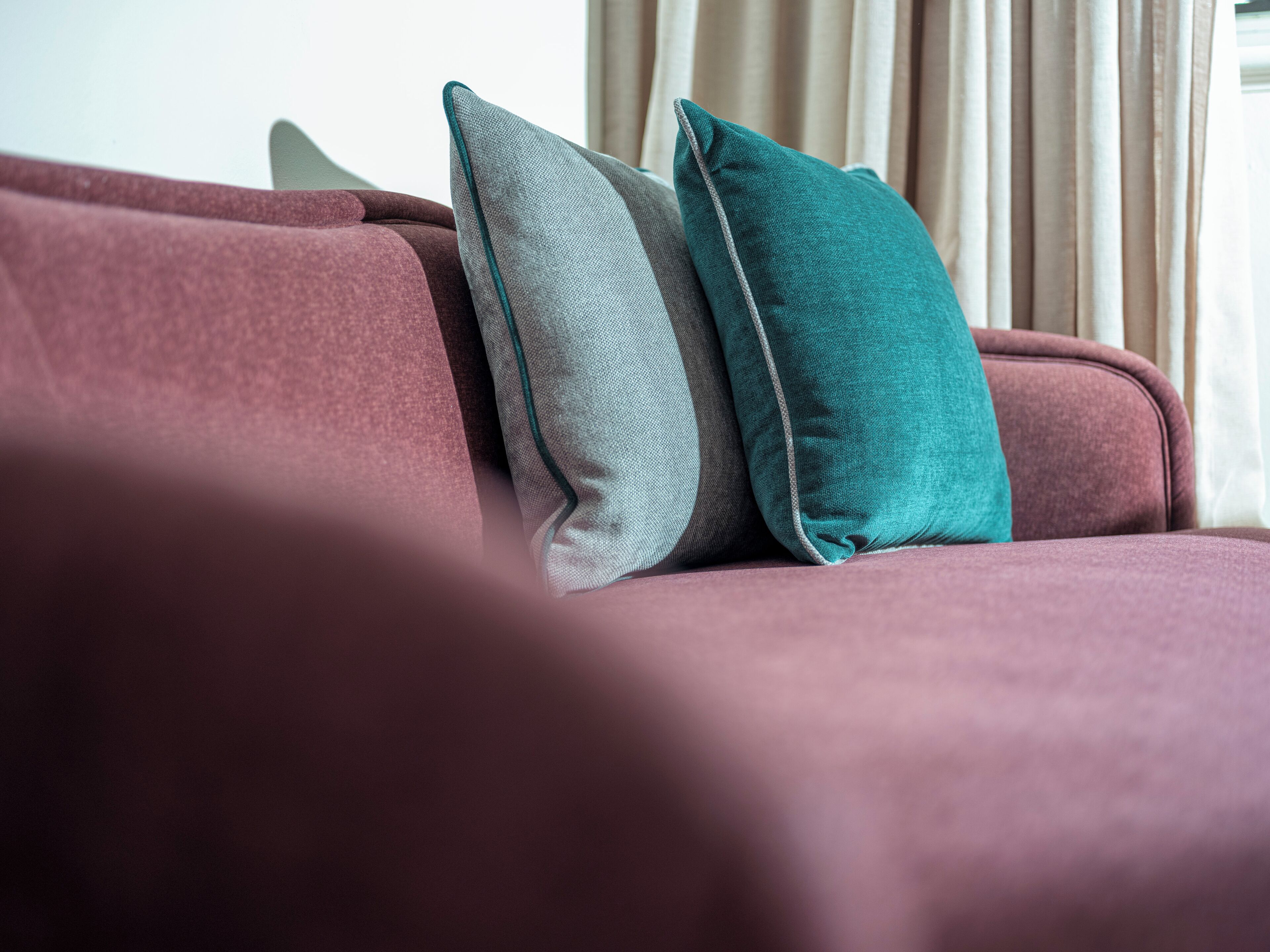 Primer plano de un sofá con tres almohadones de distintos colores.