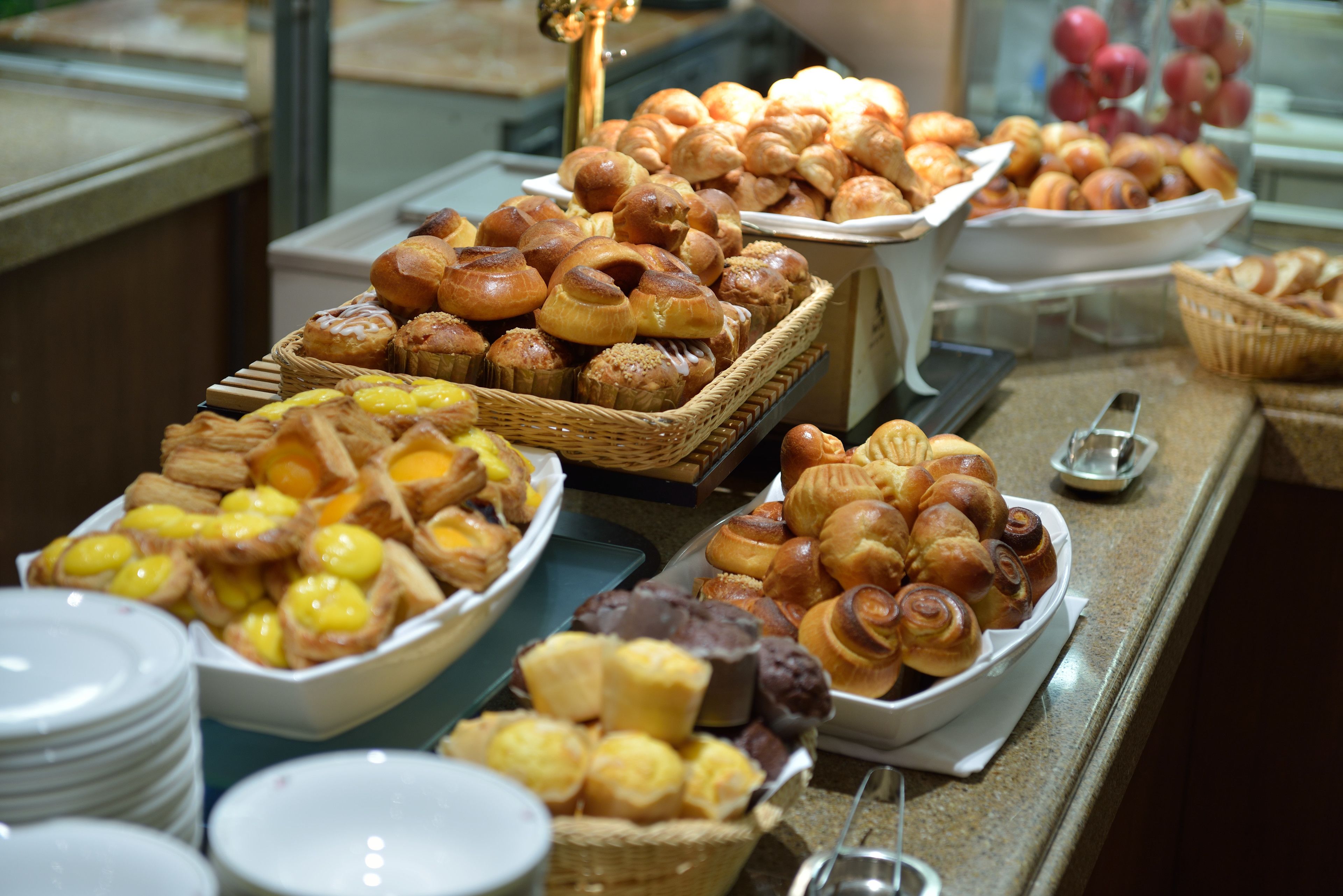 A buffet with various baked goods including pastries and bread.