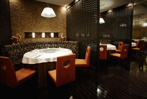 A restaurant with a brick wall, wooden blinds, and a round table with chairs.