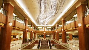 Eine großzügige Lobby mit einer zentralen Treppe, Holzvertäfelung und einer dekorativen Decke.