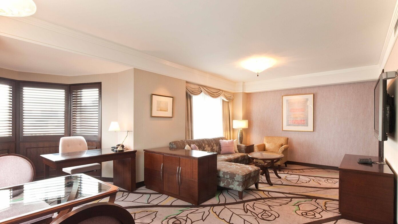 Une chambre d’hôtel équipée d’un bureau, d’un canapé, d’une chaise, d’une petite table, d’un meuble et d’une télévision.