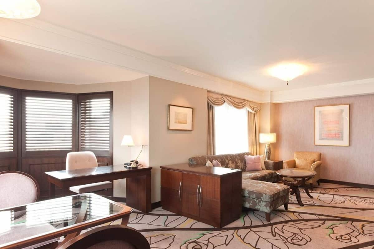 Une chambre d’hôtel équipée d’un bureau, d’un canapé, d’une chaise, d’une petite table, d’un meuble et d’une télévision.