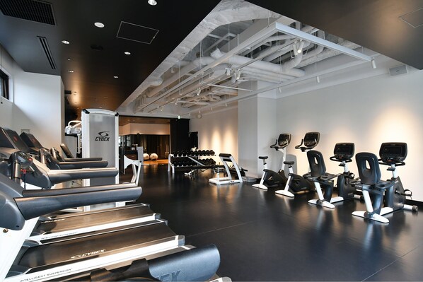 A gym with treadmills, elliptical machines, and dumbbells.