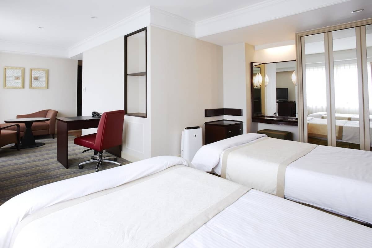 Une chambre d’hôtel avec deux lits, un bureau, une chaise, une télévision et un miroir.