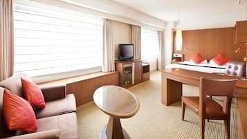 A hotel room with a bed, a desk, a television, a sofa, and a chair.