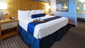 Een hotelkamer met een groot bed, twee nachtkastjes, een spiegel en een vloerbedekking.