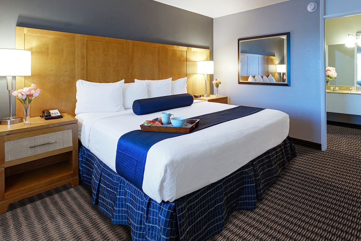 Ein Hotelzimmer mit einem großen Bett, zwei Nachttischen, einem Spiegel und einem Teppichboden.