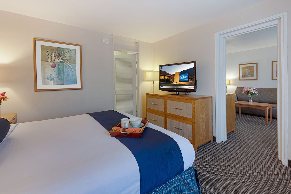Ein Hotelzimmer mit Bett, Fernseher, Kommode und Schreibtisch mit Stuhl.