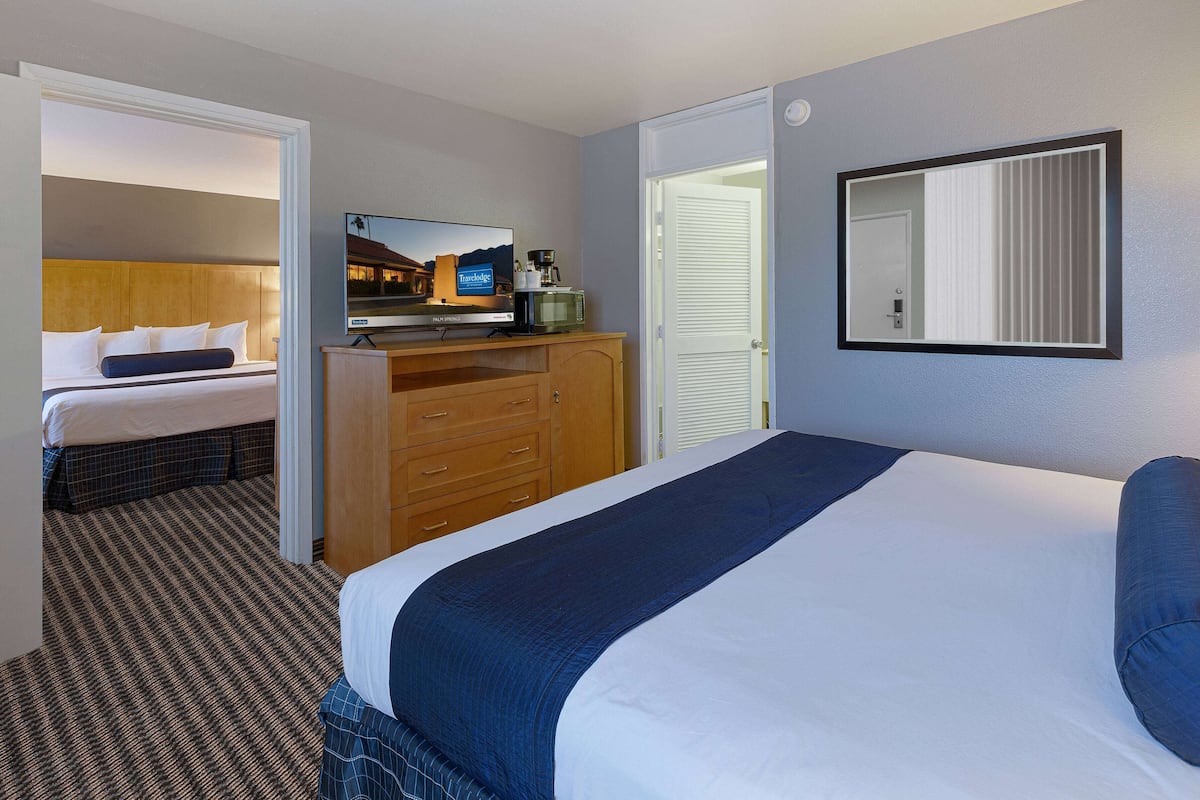 Ein Hotelzimmer mit einem großen Bett, einem Fernseher, einem Schreibtisch mit Computer und einem Kleiderschrank.
