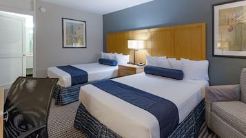Quarto de hotel com duas camas, uma escrivaninha, uma cadeira e uma mesa de cabeceira com abajur.