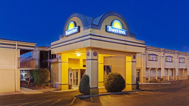 A Days Inn hotel with a two-story structure, a parking lot, and a clear sky.