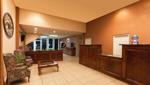 A lobby with a reception desk, a coffee table, and floral armchairs.
