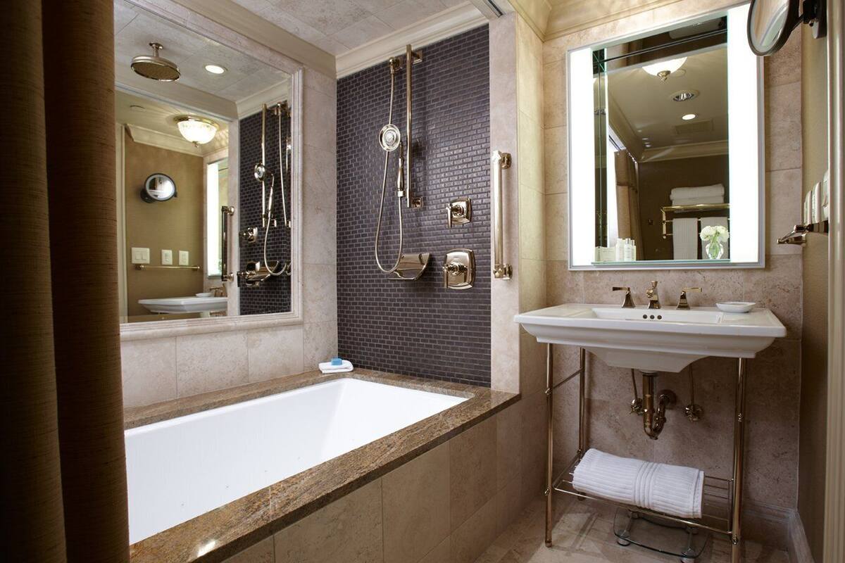 A modern bathroom with a large bathtub, a separate shower area, and a vanity with a sink and mirror.