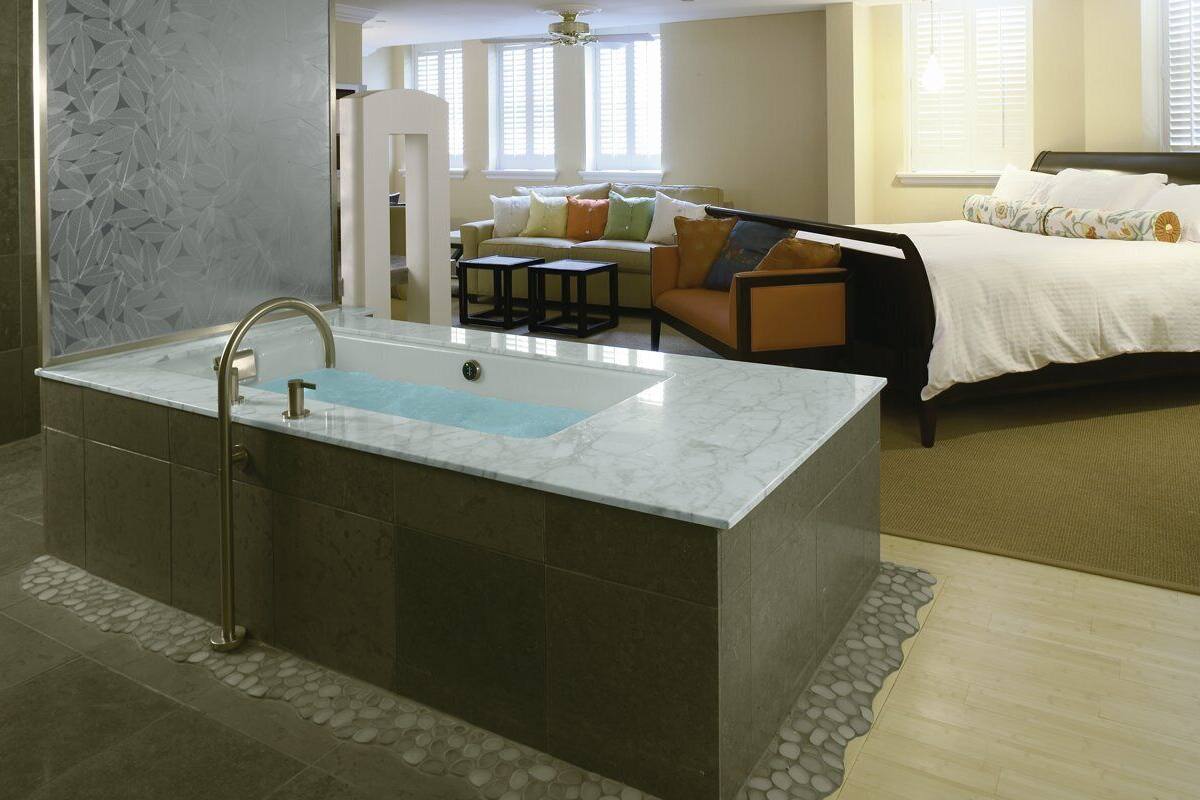 A modern bathroom with a large bathtub, a separate sink, and a shower area.